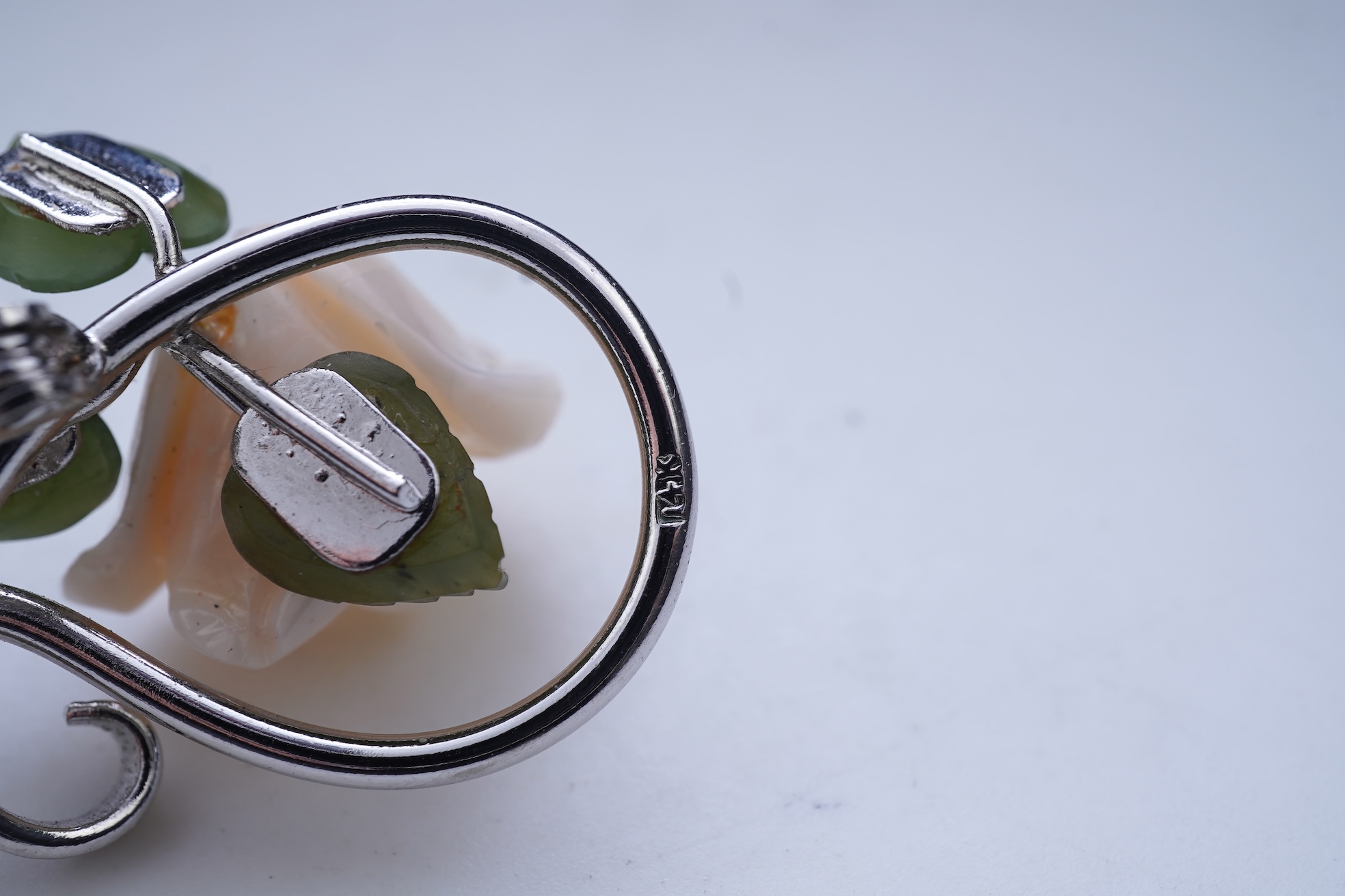 A white coral and nephrite brooch, designed as a spray of roses in carved white coral with nephrite leaves, on a scrolled white gold mount, length 5.5cm, stamped 14K, gross weight 11 grams